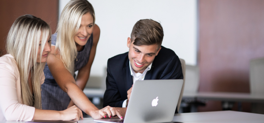 Students and advisor looking up attendance costs on laptop