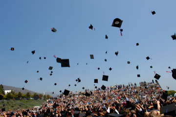 Pepperdine alumni throwing their caps into the air at commencement ceremony