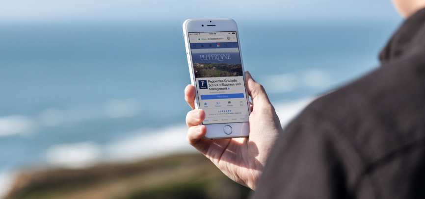 Person looking at Pepperdine's social media facebook page while at the beach