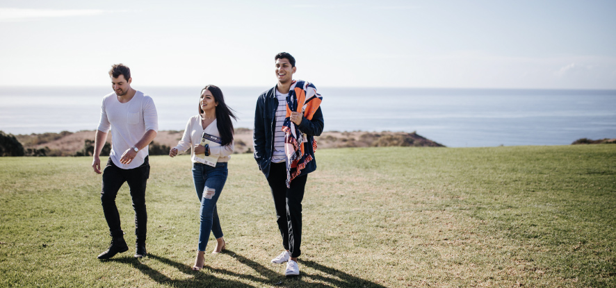 Pepperdine students walking around alumni park with ocean view in background on sunny day