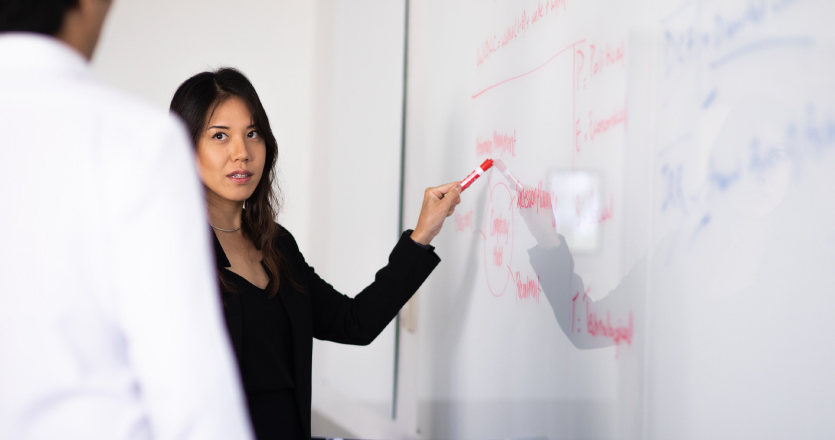 Student at whiteboard working through finance problem