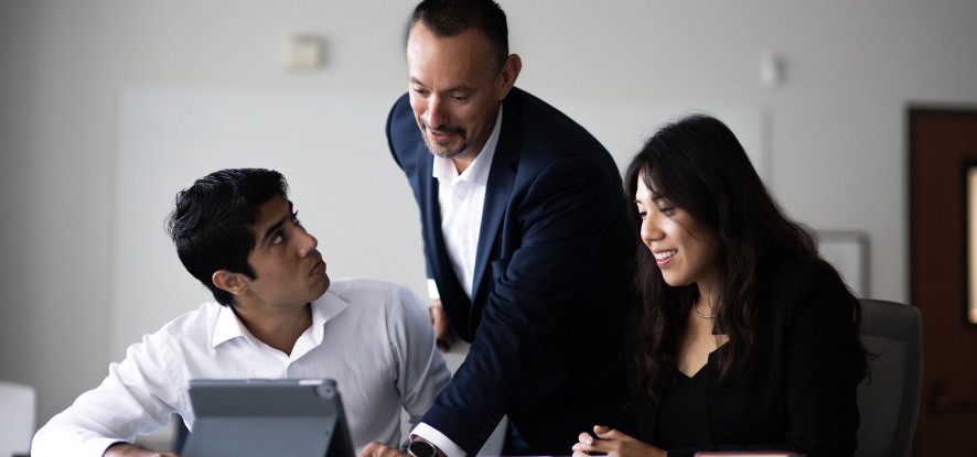 Two Master's in Business students studying with professor inside of classroom setting