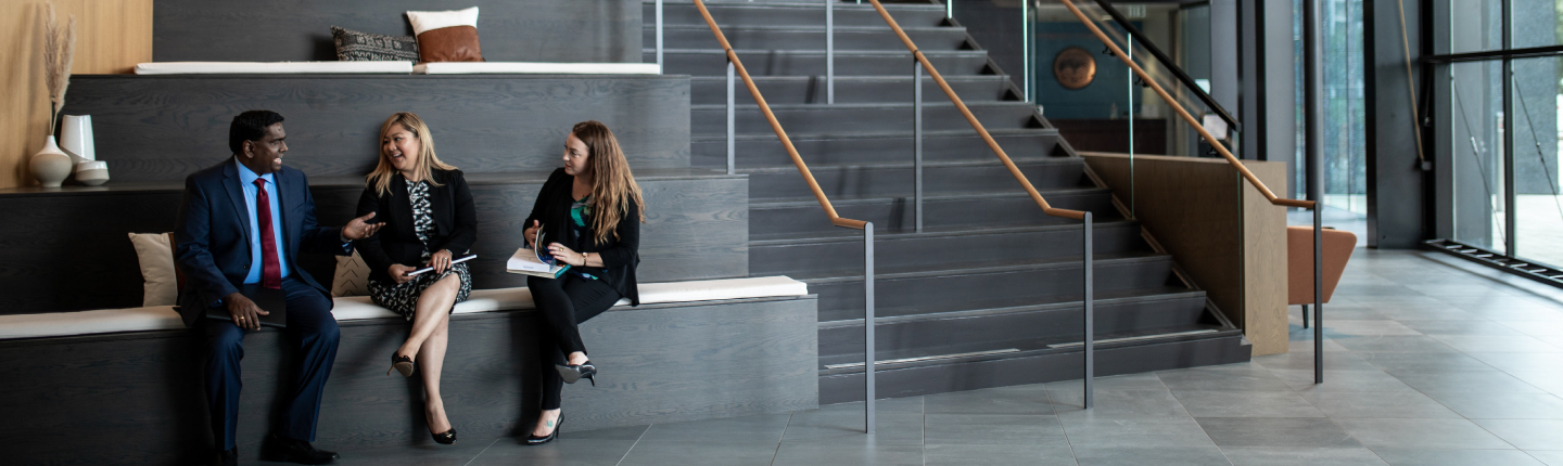 Three students chatting on lobby stairs on-campus