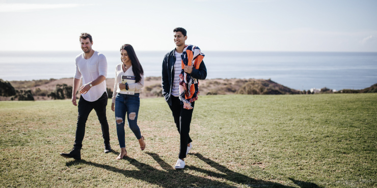 Three students walking on lawn at Pepperdine University